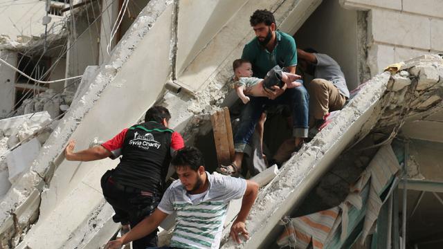 Syrian men remove a baby from the rubble of a destroyed building following a reported airstrike in the Qatarji neighbourhood of Aleppo 