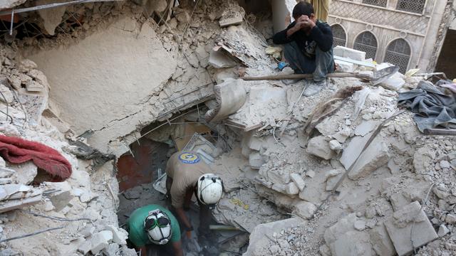 Syrian civil defence volunteers, known as the White Helmets, search for victims amid the rubble of destroyed buildings following a government airstrike on the rebel-held neighbourhood of Bustan al-Basha in the northern city of Aleppo 