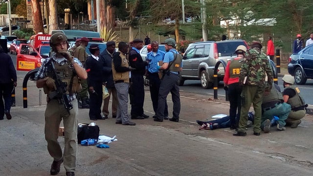 Unidentified U.S. Embassy personnel and Kenyan security forces stand near the body, right, of a man who was killed outside the U.S. Embassy in Nairobi, Kenya, Oct. 27, 2016. 