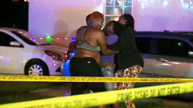 A group reacts after an 8-year-old boy was fatally shot while walking home from a birthday party near his home in Dania Beach, Florida, on Dec. 28, 2016. 