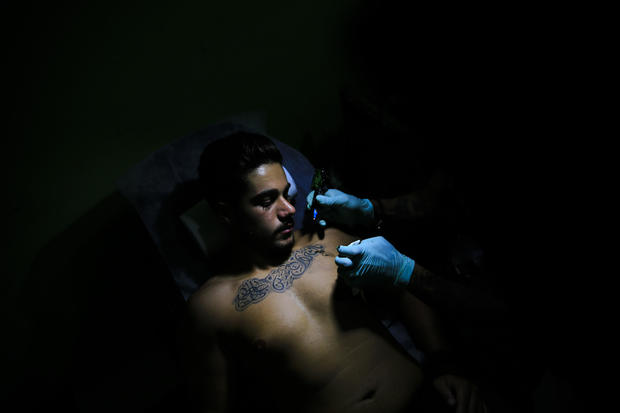 Tattoo artist Hussein Al-Hussein inks the chest of client Alodi Issa, 22, with Shiite Muslim religious slogans at his tattoo shop in a southern suburb of Beirut, Lebanon, on July 22, 2016. The tattoo in Arabic reads, “Oh, the revenge for Hussein. Ali, Fat 