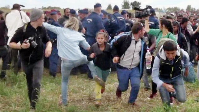 A Hungarian TV camerawoman kicks a child as she runs with other migrants from a police line during disturbances in Roszke, Hungary, in this image capture made on Sept. 9, 2015. 