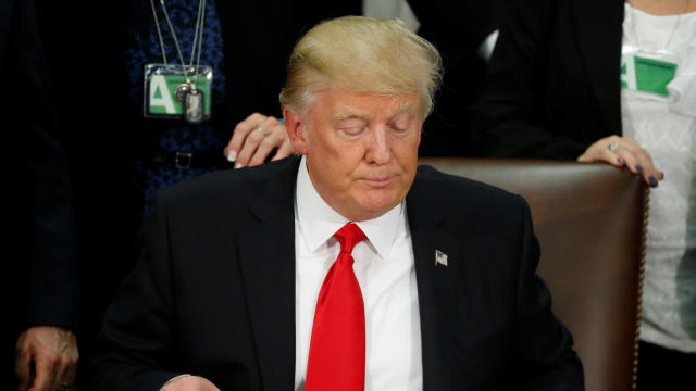 President Trump reads an executive order before signing it at Homeland Security headquarters in Washington Jan. 25, 2017. 