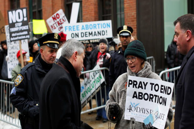 An anti-Planned Parenthood protester walks by pro-abortion-rights protesters gathered outside the Planned Parenthood - Margaret Sanger Health Center in Manhattan, New York, Feb. 11, 2017. 
