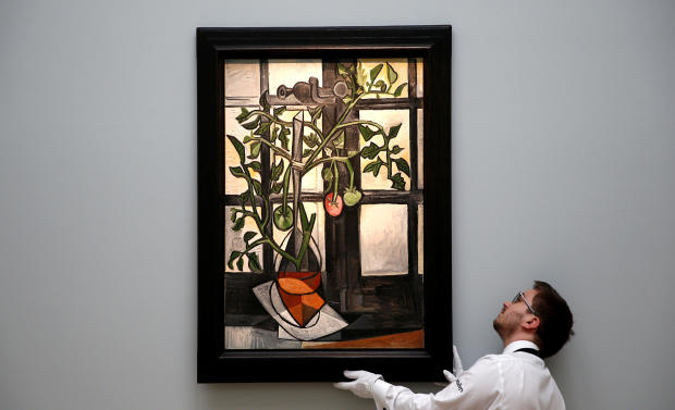 A worker poses with Pablo Picasso’s “Plant de tomates” ahead of an upcoming sale at Sotheby’s auction house in London, Britain, Feb. 22, 2017. 