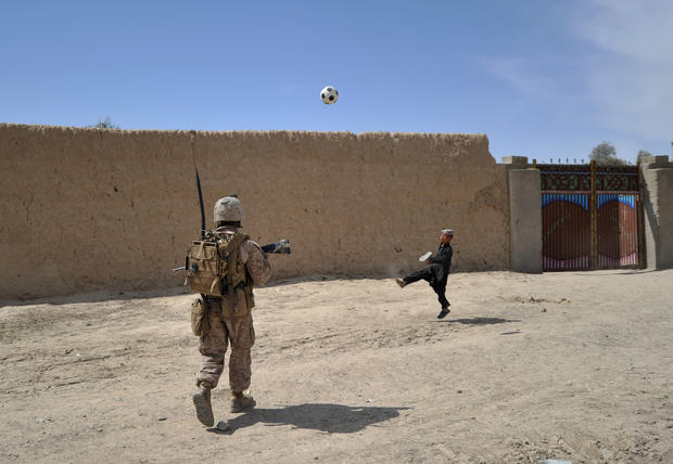 An Afghan child plays football as a US M 