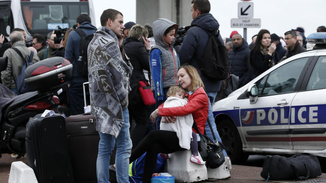 Travelers wait outside the Orly airport, south of Paris, March 18, 2017. 