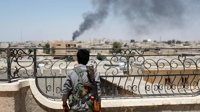 A Kurdish fighter from the People's Protection Units looks at a pillar of smoke after a coalition airstrike in Raqqa, Syria, June 16, 2017. 