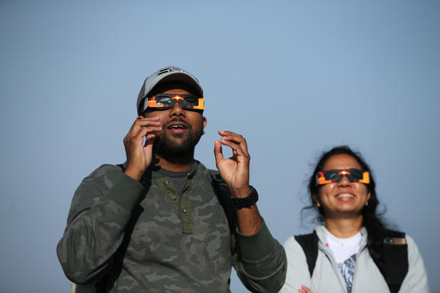 People use solar viewing glasses as the sun emerges through fog cover before the solar eclipse in Depoe Bay 