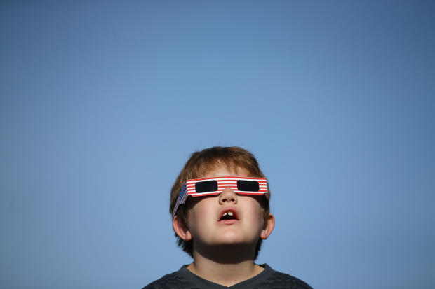 A boy uses solar viewing glasses as the sun emerges through fog cover before the solar eclipse in Depoe Bay 
