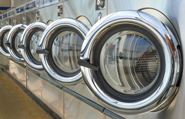 Row of industrial laundry machines in laundromat. 