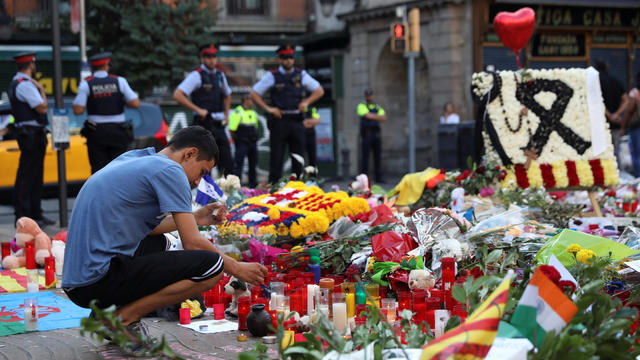 A man lights a candle at an impromptu memorial where a van crashed into pedestrians at Las Ramblas in Barcelona 