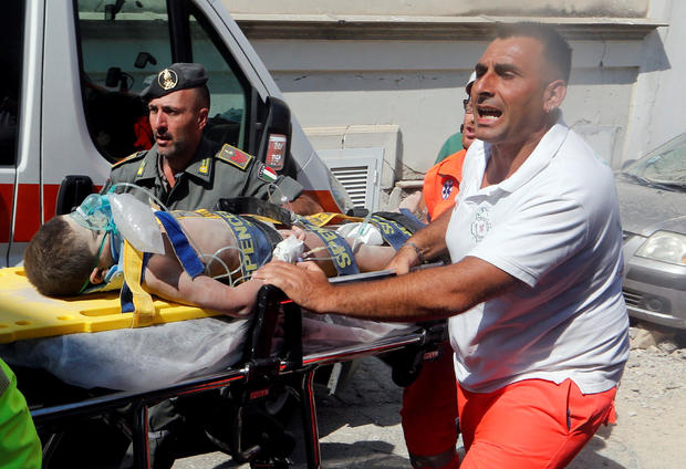 Rescue workers carry a child after an earthquake hit the island of Ischia, in Naples 