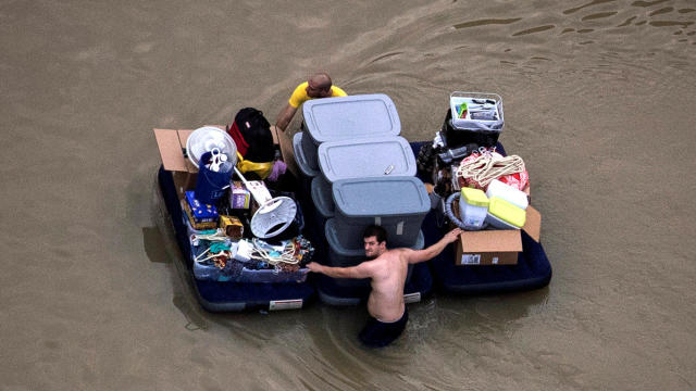Residents wade with their belongings through floodwaters brought by Tropical Storm Harvey in Houston, Texas, Aug. 30, 2017. 