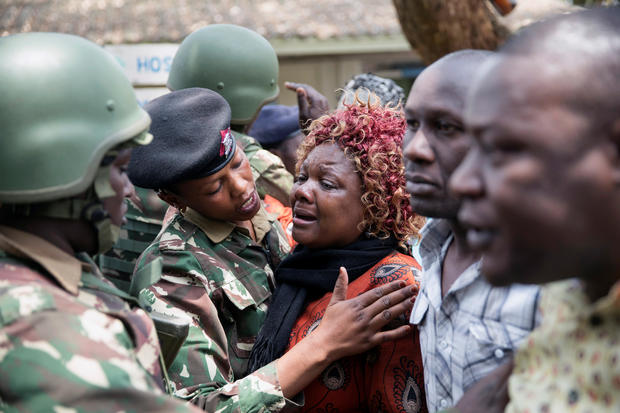 A Kenyan police officer comforts a relative at the scene where seven Kenyan teenage schoolgirls died and 10 more were hospitalized after a fire engulfed their boarding school dormitory in Nairobi 