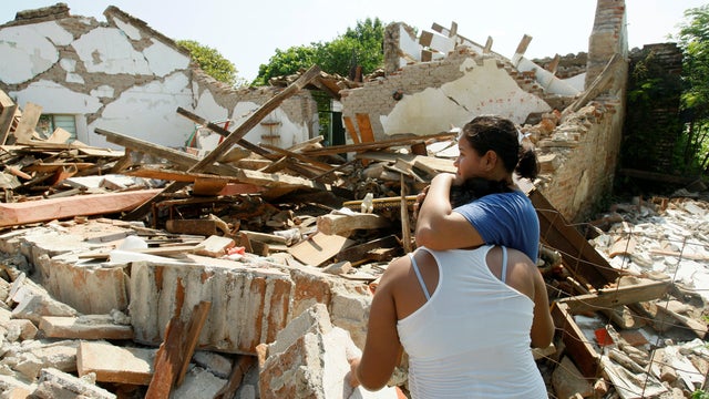 Women hug while standing next to a destroyed house after an earthquake struck the southern coast of Mexico late on Thursday, in Union Hidalgo 