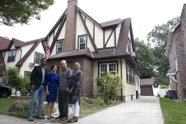 Abdi Iftin, left, of Somalia; Uyen Nguyen, second from left, of Vietnam; Eiman Ali, right, of Somalia but born in Yemen; and Ghassan al-Chahada of Syria pose for a photo outside President Trump's boyhood home in the Jamaica Estates neighborhood of the Que 