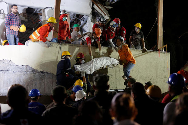 Rescue workers remove a dead body after searching through rubble in Mexico City 