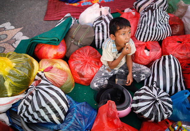 A boy sits amongst his family belongings after he was evacuated from a village located along the slopes of Mount Agung at a temporary shelter in Rendang, Bali 