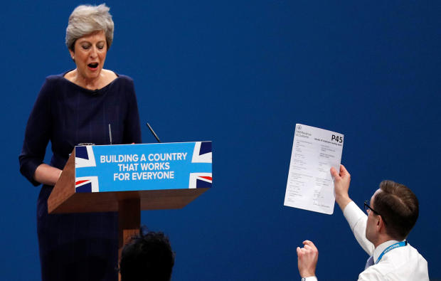 A member of the audience hands a P45 form (termination of employment tax form) to Britain's Prime Minister Theresa May as she addresses the Conservative Party conference in Manchester, England, Oct. 4, 2017. 