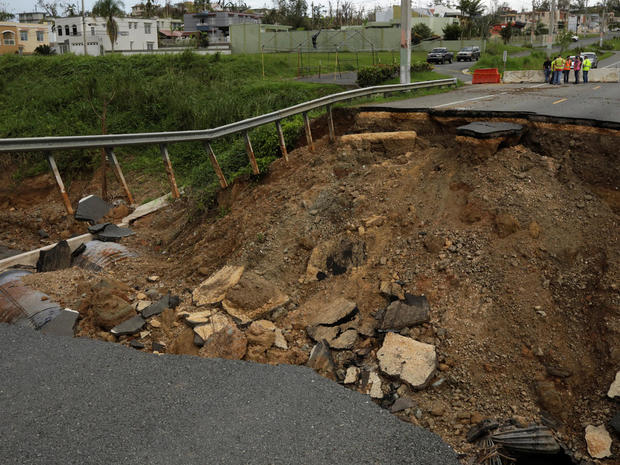 Workers prevent cars from driving down a road washed out during Hurricane Maria in San Sebastian, Puerto Rico 