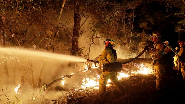 A firefighting crew drives pass a business destroyed in wildfire that tore through Santa Rosa, California 
