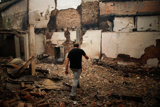 A man walks through burned houses following a forest fire in Pinheiro do Azere 