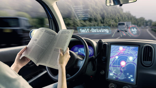 cockpit of autonomous car. a vehicle running self driving mode and a woman driver reading book. 