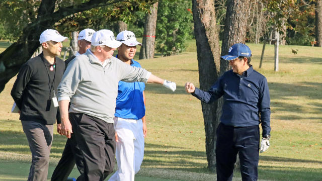 U.S. President Donald Trump gestures to Japan's Prime Minister Shinzo Abe as Japanese professional golfer Hideki Matsuyama looks on, as they play golf at the Kasumigaseki Country Club in Kawagoe, Japan 