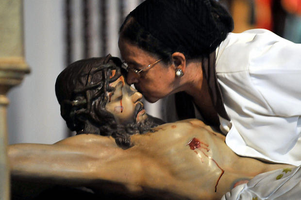 A woman kisses an statue of Jesus Christ 