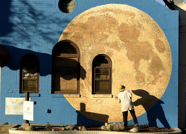 Painter paints beautiful moon on the side of a restaurant in Denver 