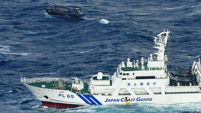 A Japan Coast Guard vessel sails near a drifting wooden boat carrying men identified as North Koreans off Matsumae on the northern Japanese island of Hokkaido, in this photo taken by Kyodo Nov. 29, 2017. 