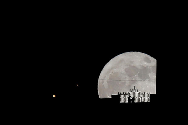 People walk along the "Puente Nuevo" (New Bridge) as they are silhouetted against the supermoon during it rise in Ronda 