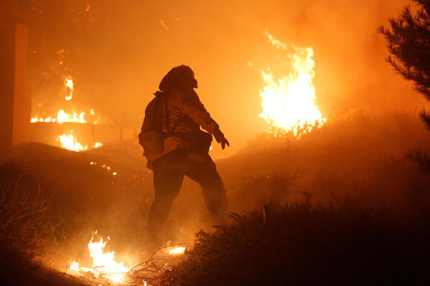 A firefighter stomps out small embers near a home threatened by the Creek Fire in Sylmar, California 