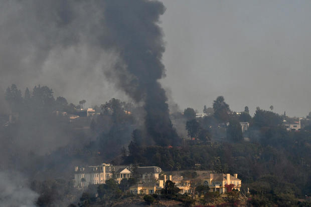 A home burns as a wildfire dubbed the Skirball Fire moves through a wealthy neighborhood on the west side of Los Angeles 