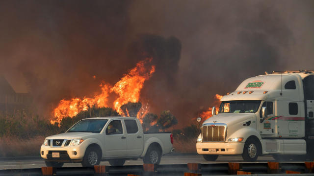 Vehicles pass a fire on the southbound side of the U.S. 101 freeway in Mondos Beach, west of Ventura, California, on Dec. 7, 2017. 