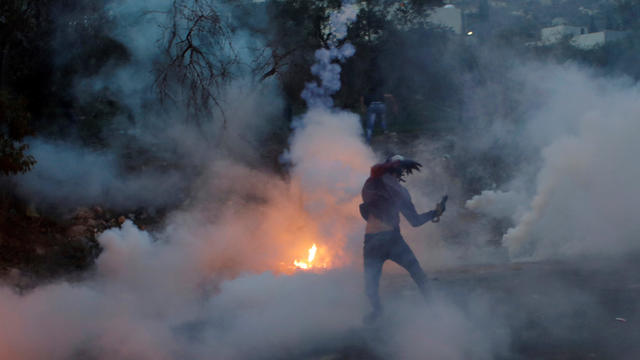 Palestinian demonstrator hurls back a tear-gas canister fired by Israeli troops during clashes at a protest near the West Bank city of Nablus 