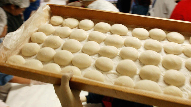 A tray of Japanese rice cakes called mochi is carried out of a work room where women are forming cooked and pounded rice into small cakes, Dec. 14, 2003, at the Buddhist Temple in San Diego, California. 