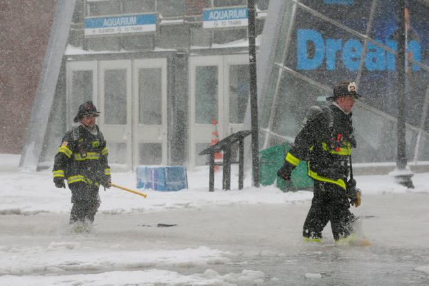 Boston firefighters wade through a street flooded from tidal surge during Storm Grayson in Boston 