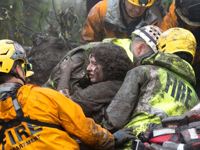 Emergency personnel carry a woman rescued from a collapsed house after a mudslide in Montecito