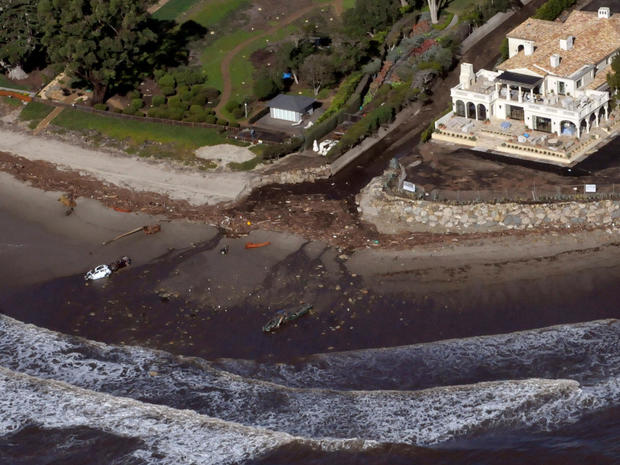 An aerial photo showing two vehicles submerged in the surf amidst debris from a mudslide due to heavy rains in Montecito 