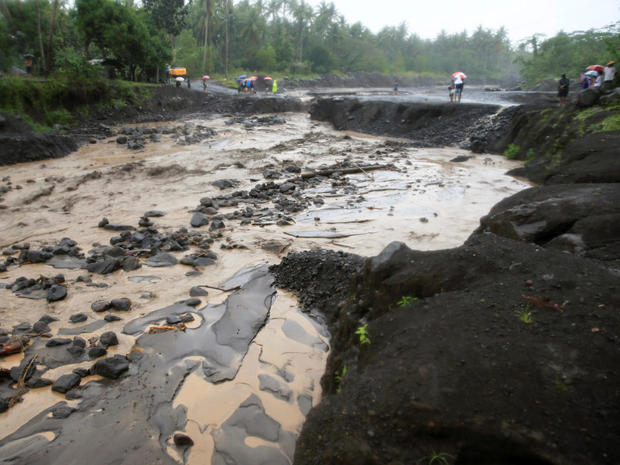 Residents watch a river with lahar flowing from Mount Mayon volcano in Guinobatan, Albay province, south of Manila 