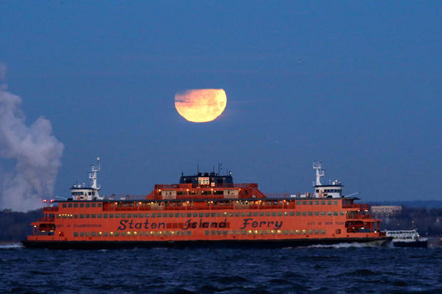 The "Super Blue Blood Moon" sets behind the Staten Island Ferry, seen from Brooklyn, New York 