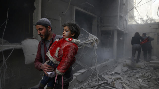 Man holds child after airstrike in besieged town of Douma, Eastern Ghouta, Damascus 