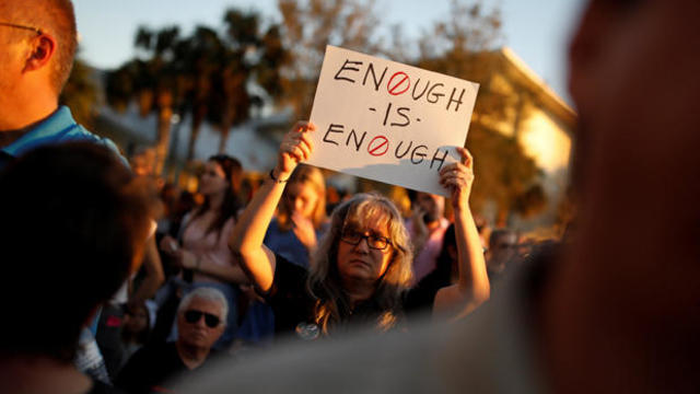 A woman holds a placard during a candlelight vigil for victims of yesterday's shooting at nearby Marjory Stoneman Douglas High School, in Parkland 