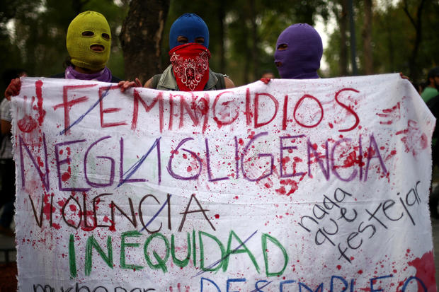 Hooded women hold a banner during a demonstration on International Women's Day in Mexico City 