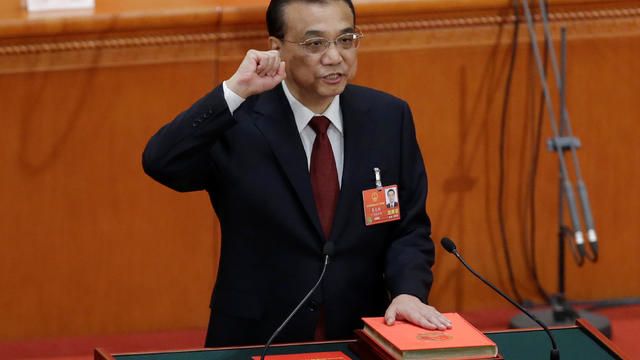 Chinese Premier Li Keqiang with his hand on the Constitution takes the oath, after he is voted as the premier for another term, at the sixth plenary session of the NPC at the Great Hall of the People in Beijing 