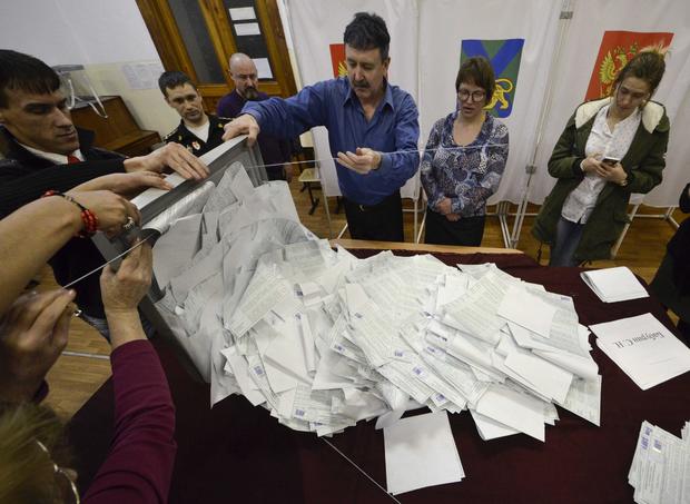 Members of a local election commission empty a ballot box before starting to count votes during the presidential election in Vladivostok 