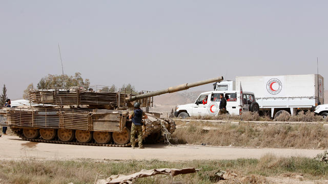 Syrian army military tank and Syrian Arab Red Crescent truck are seen at the entrance of Harasta 