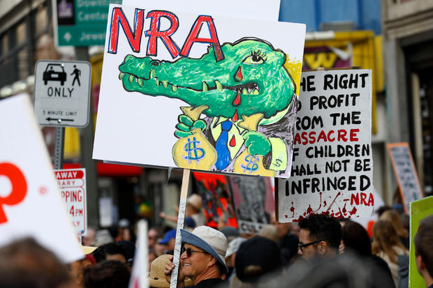 People walk with signs against the NRA during "March for Our Lives", an organized demonstration to end gun violence, in downtown Los Angeles 